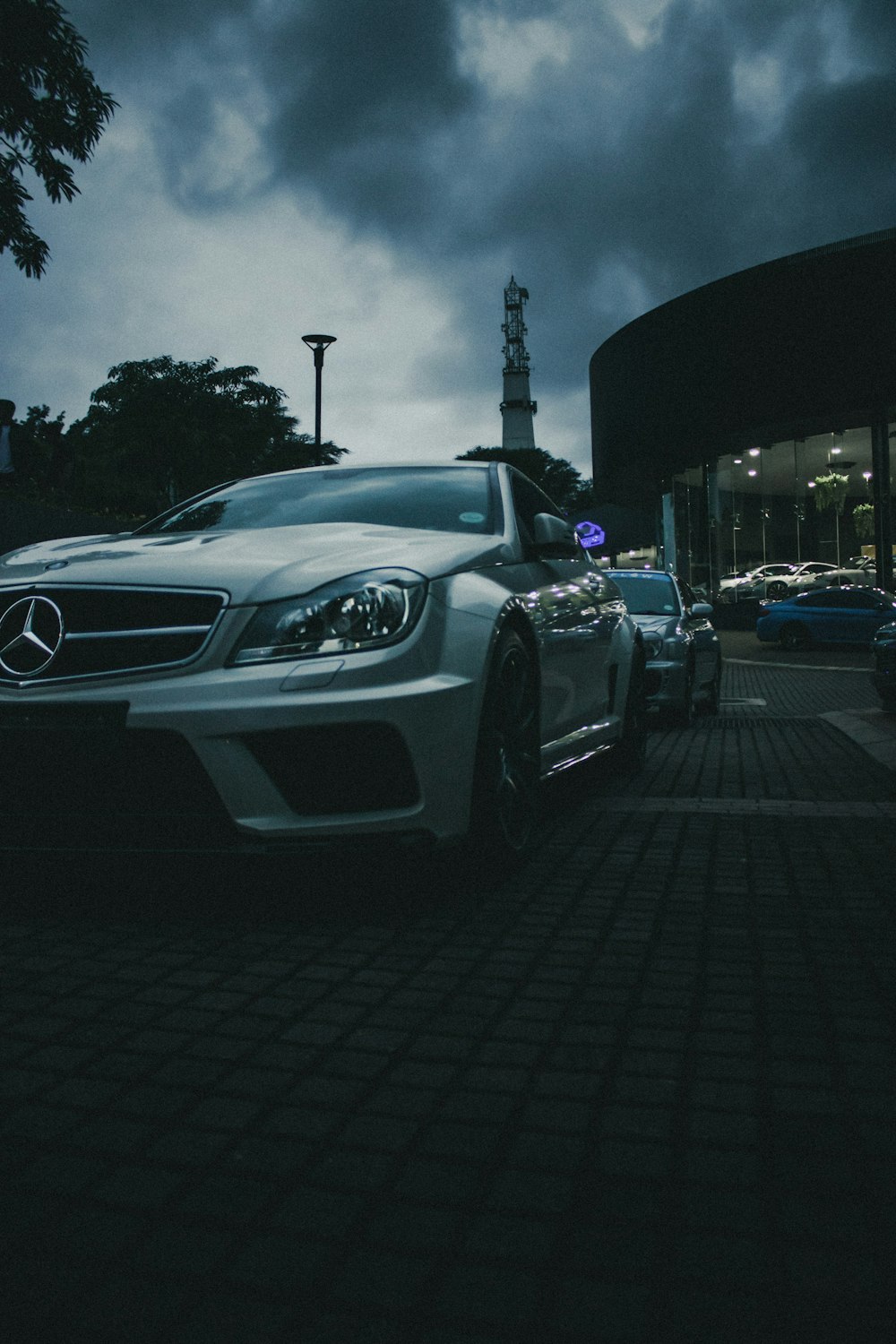 a white sports car parked on a brick road with a tower in the background