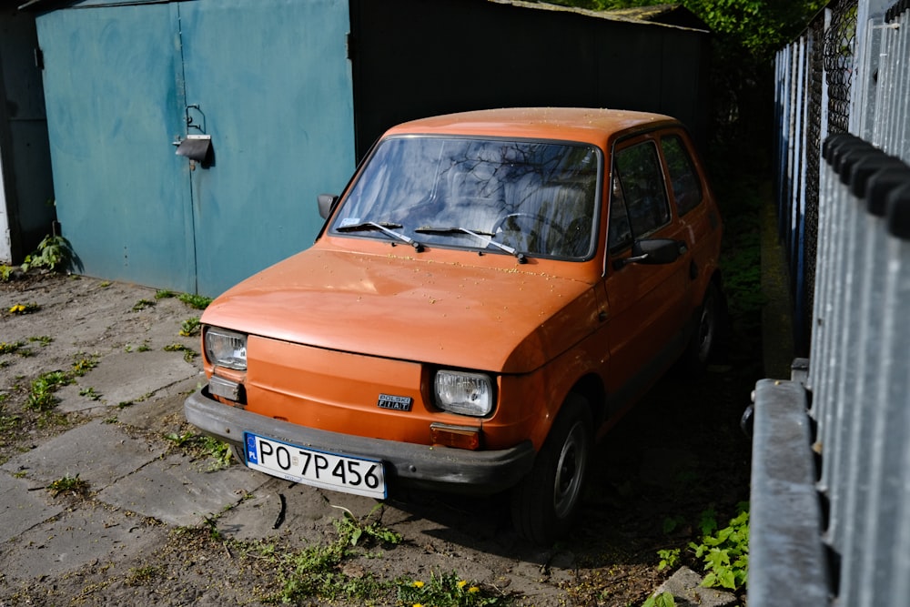 an orange car parked next to a building
