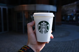 a hand holding a white coffee cup