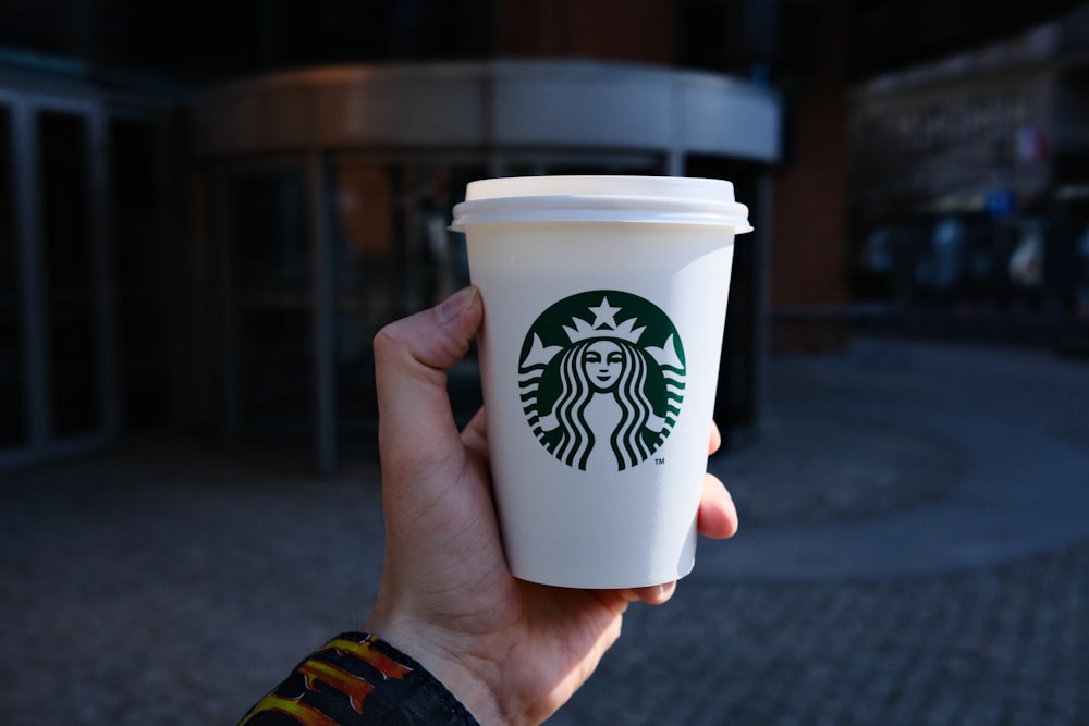 a hand holding a white coffee cup