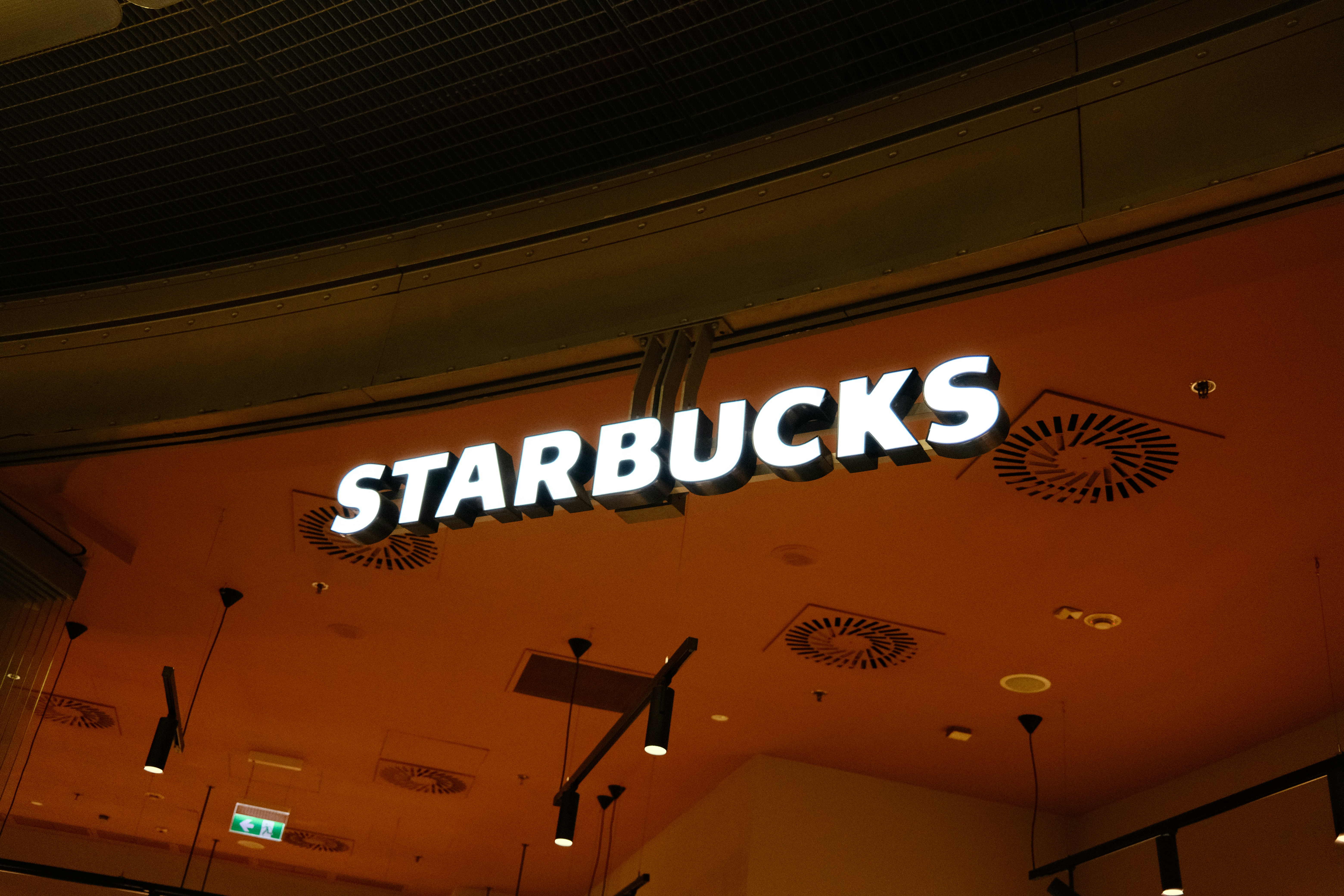 a sign on a building, Starbucks logo in shopping mall