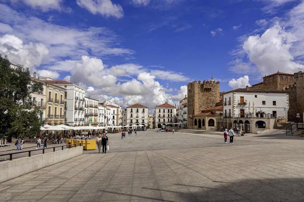 a group of people walking on a paved area with buildings in the background