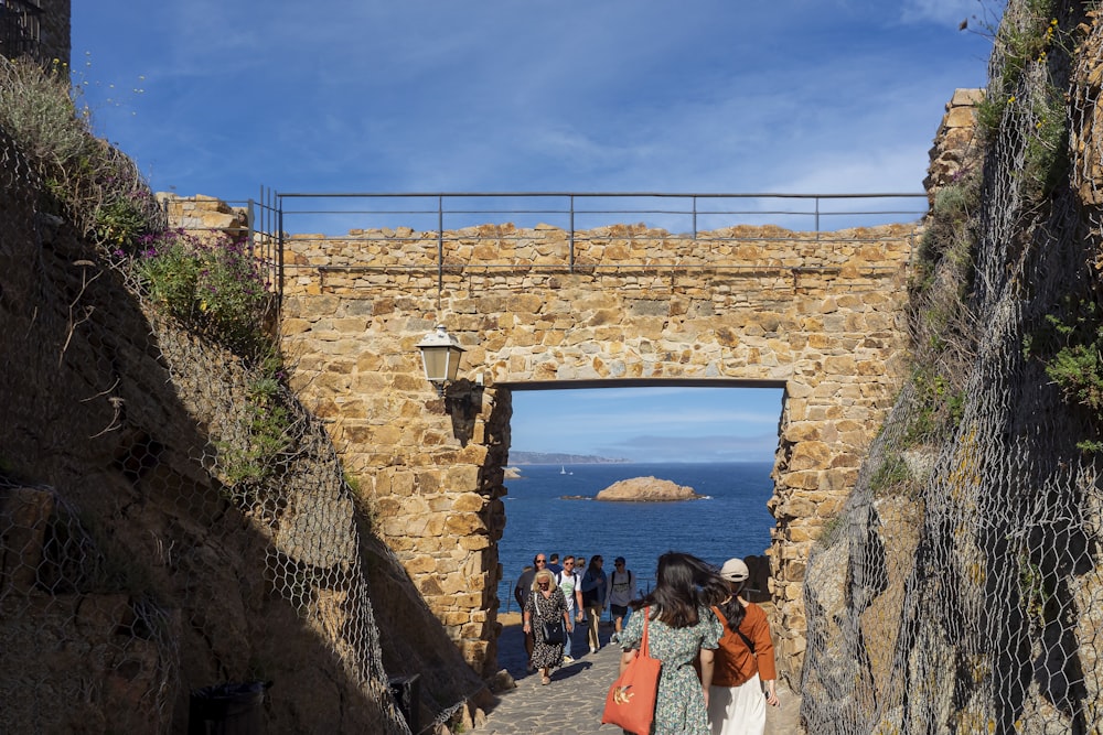 a group of people walking through a stone archway