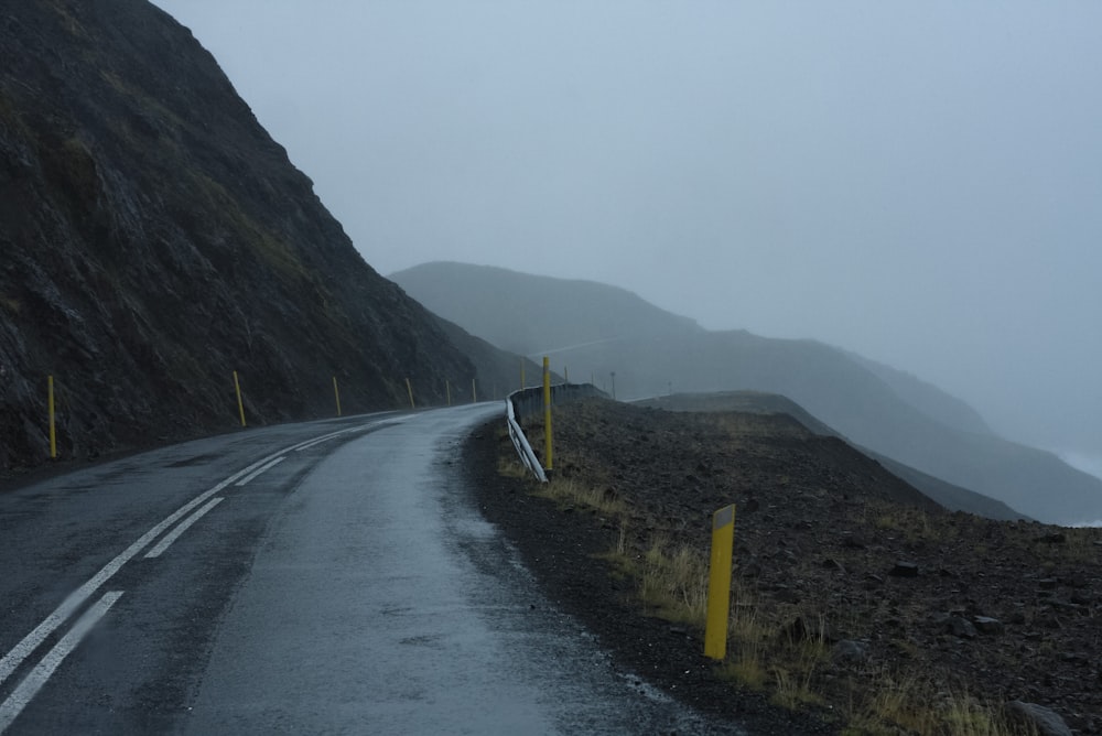 a road with yellow poles on the side and fog around it