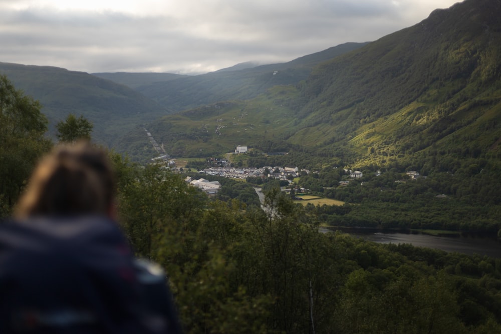 a person looking at a town in the valley between mountains