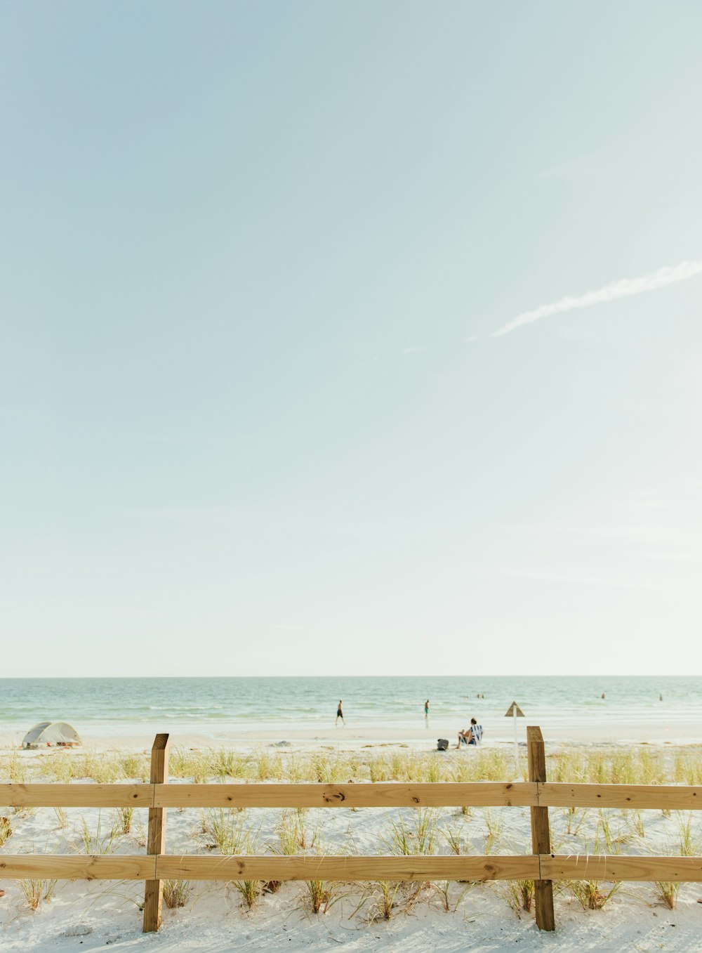 a beach with people and a fence