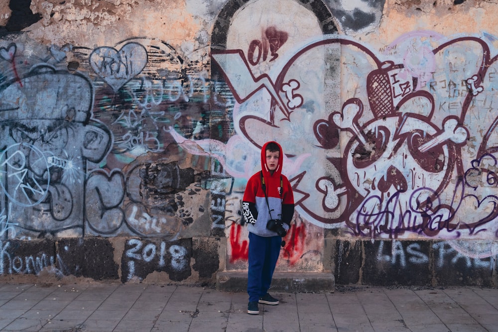 a person standing in front of a wall with graffiti