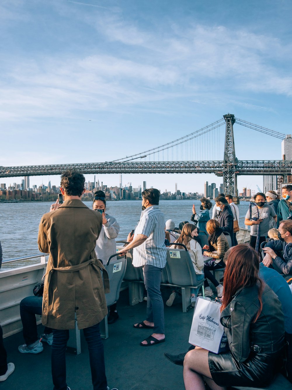 a group of people standing on a dock with a large bridge in the background