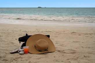 A vibrant beach scene showcasing a bottle of Sunnwaves sunblock beside a sunhat and sunglasses on warm sand.