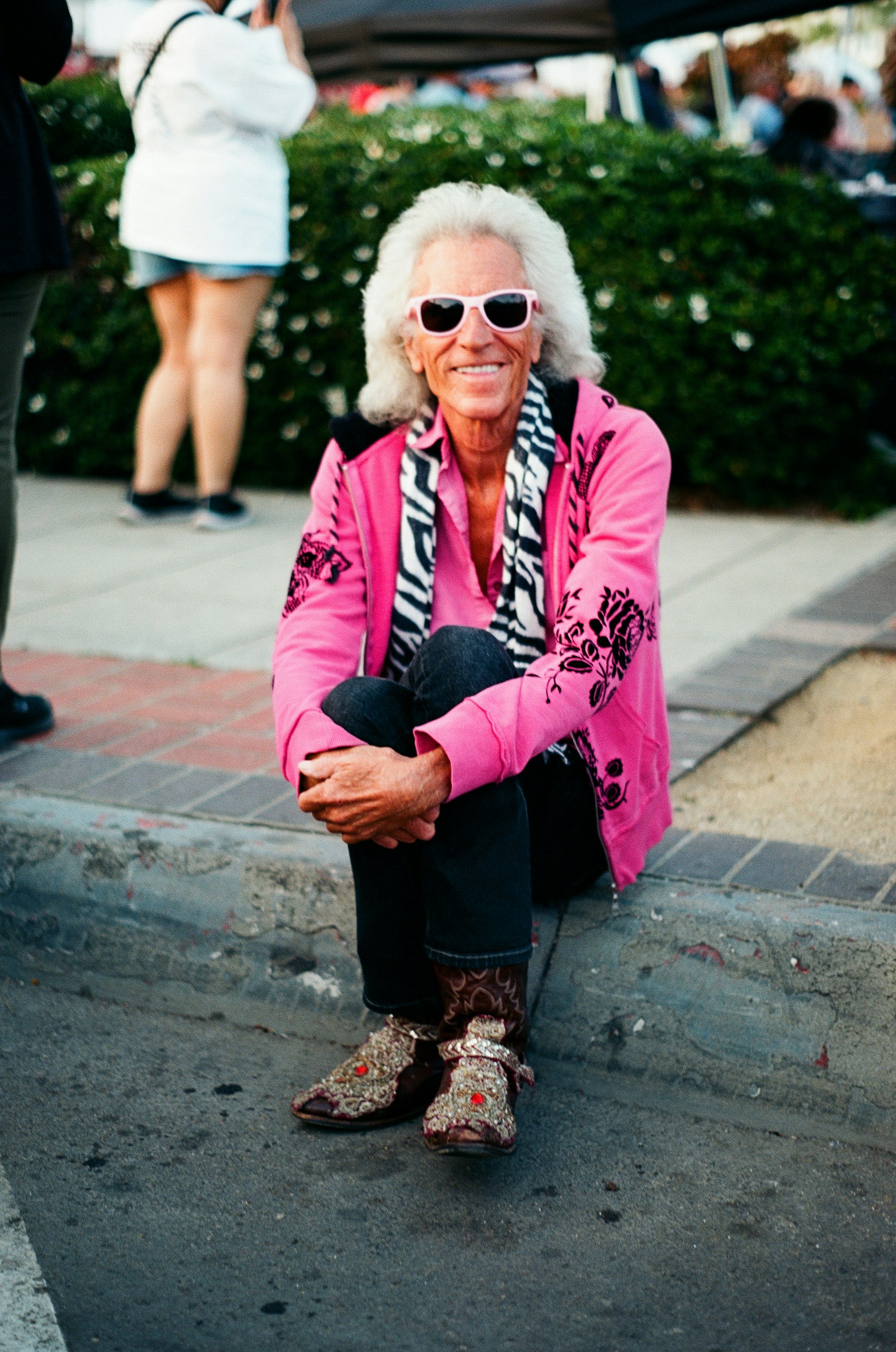 A person in a pink coat and sunglasses sitting on a curb photo – Free ...