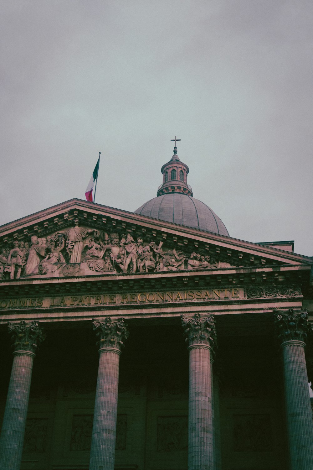 a building with a domed roof and pillars with a flag on top