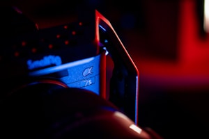 A close-up of a camera with the text 'SmallRig' and '&alpha; 7S' visible on its body. The scene is dominated by low, moody lighting with a mixture of red and blue hues, creating dramatic shadows and highlights on the camera's surface.