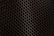 A close-up view of a metal mesh with a hexagonal pattern creating a honeycomb-like structure. The mesh is in a dark color against a black background, showcasing its intricate geometric design.
