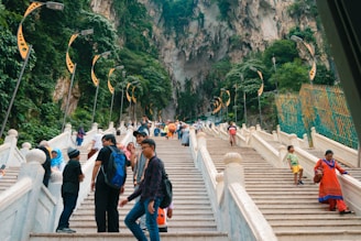 a group of people walking up stairs with Batu Caves in the background