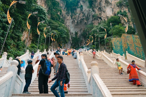 a group of people walking up stairs with Batu Caves in the background