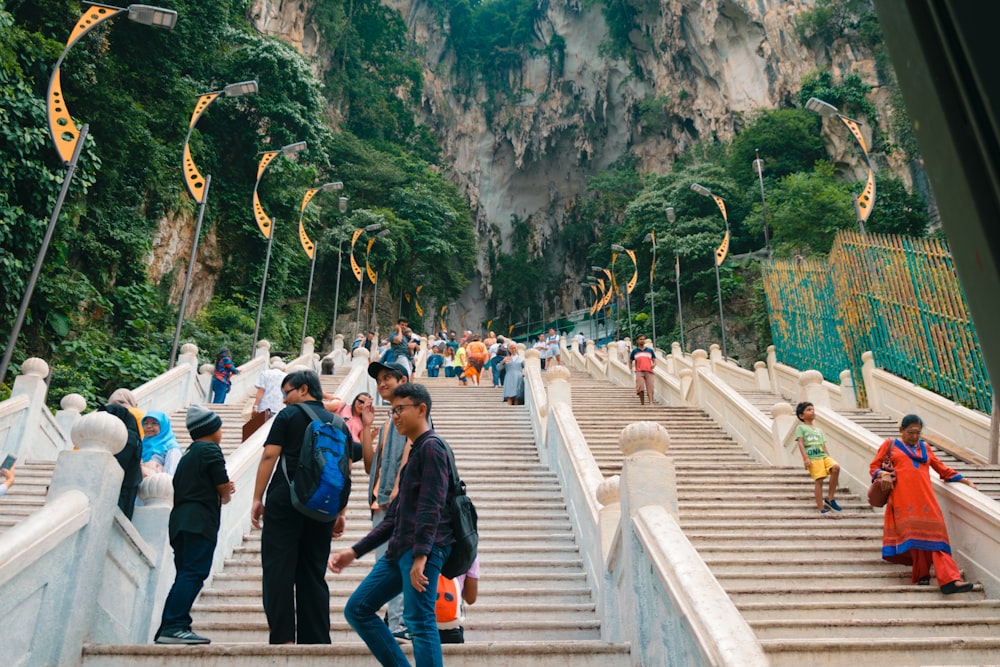 a group of people walking up stairs with Batu Caves in the background