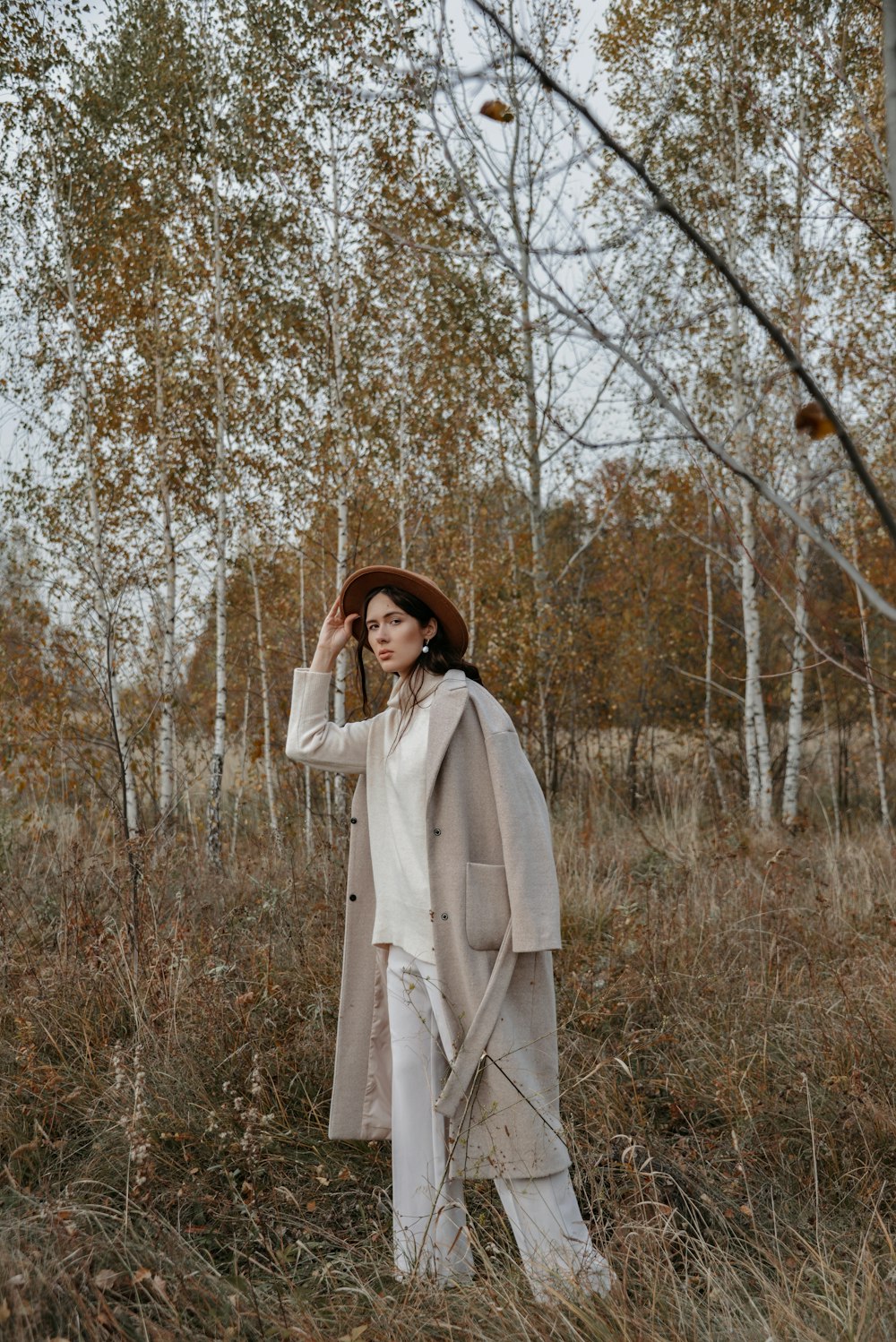 a person in a white coat and hat standing in a field of tall grass