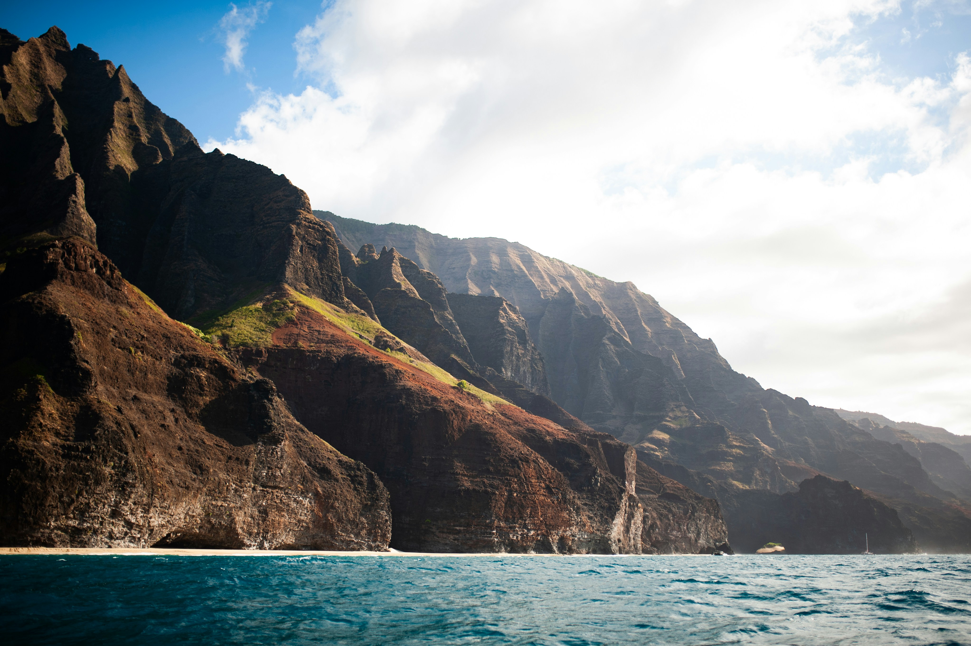 a body of water with a rocky cliff and a blue sky