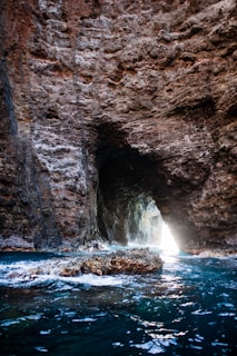 The entrance of a sea cave illuminated by sunlight, with crystal-clear water inviting exploration.