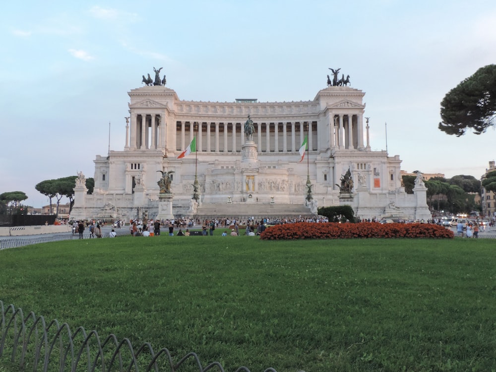 a large white building with columns and statues in front of it with Piazza Venezia in the background