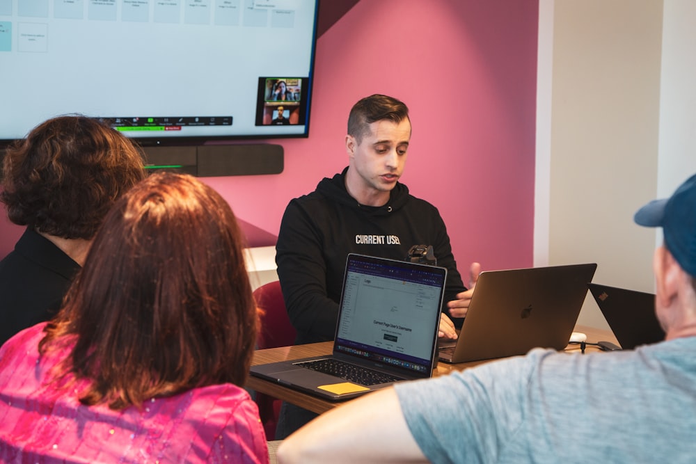 a person standing in front of a group of people using laptops