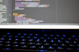 Close-up of hands typing on a keyboard with AI code on the screen.