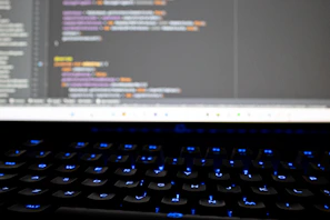 A close-up of hands typing on a keyboard with coding on the screen, symbolizing tech learning.