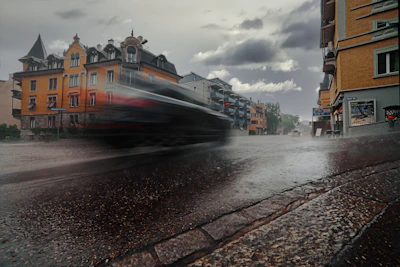 A futuristic vehicle speeding through a rainy urban street.