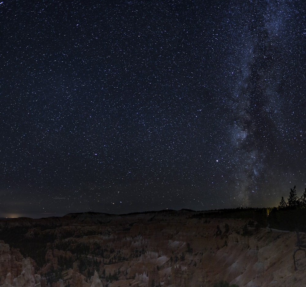 a rocky area with a starry sky above with Marfa lights in the background