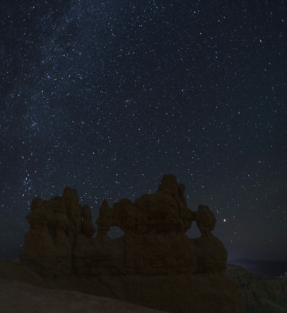 a rocky mountain with a starry sky above