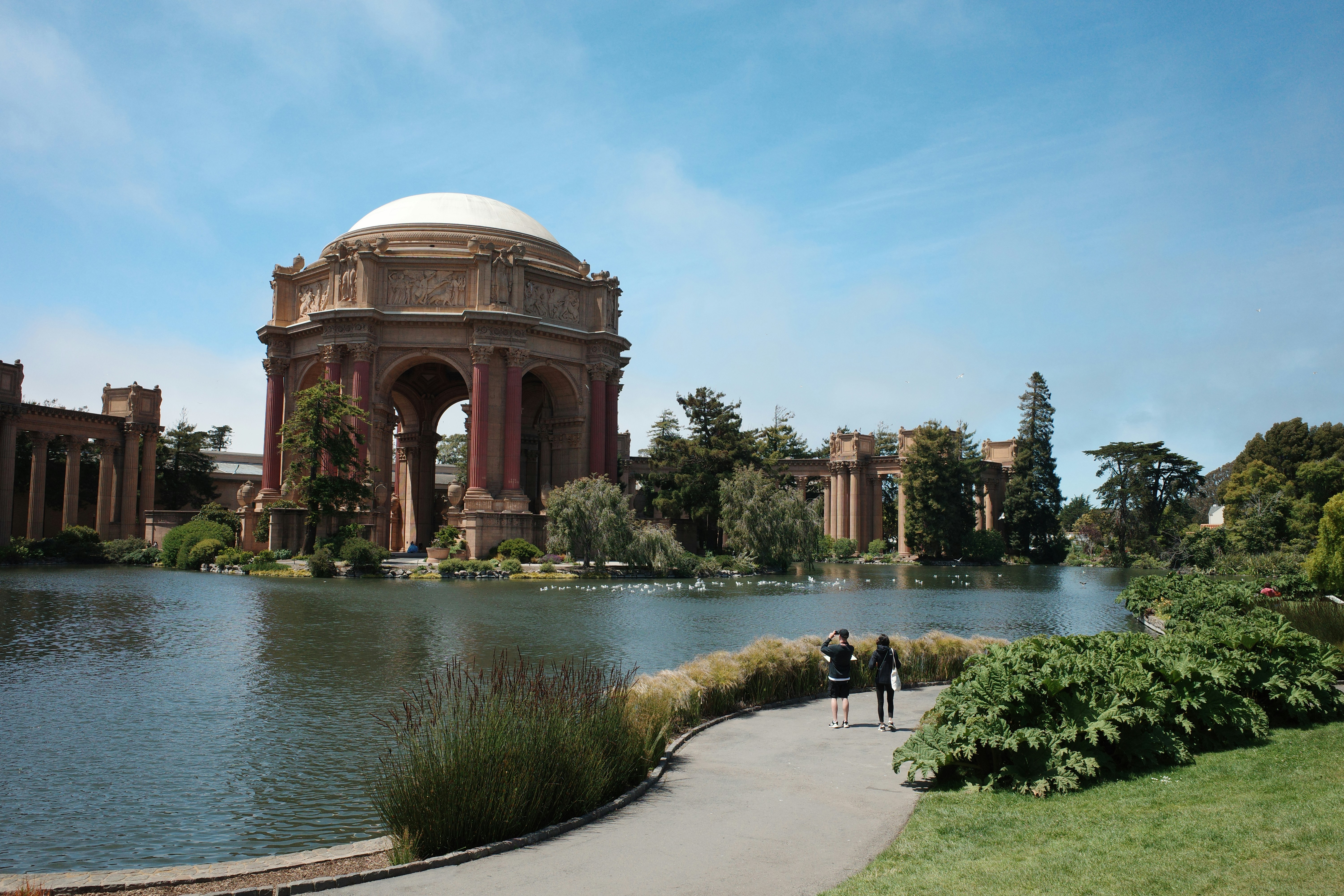 un paio di persone che camminano lungo un fiume con il Palazzo delle Belle Arti sullo sfondo