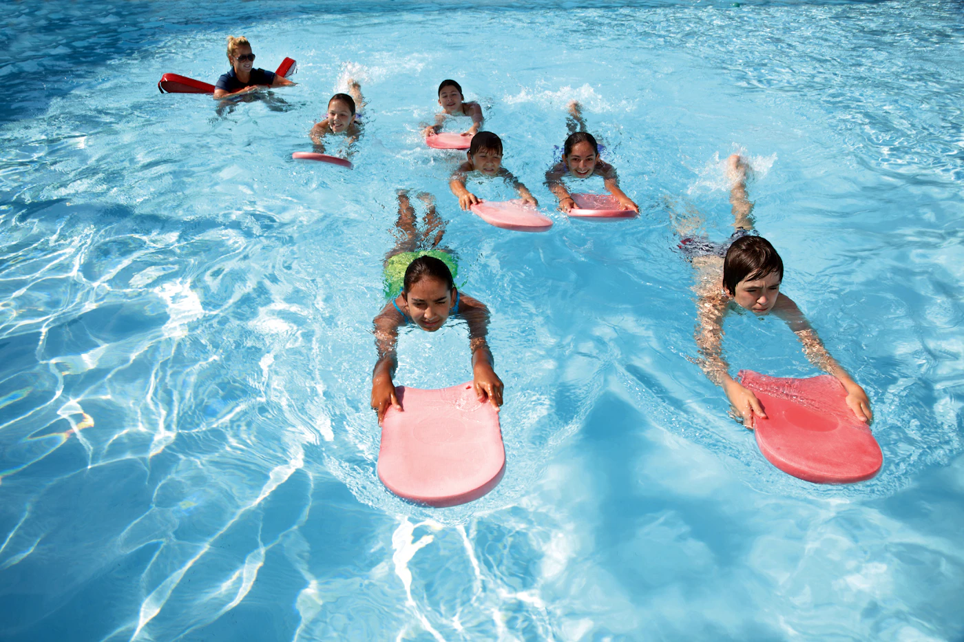 A young swimmer smiling in a bright blue learn-to-swim pool