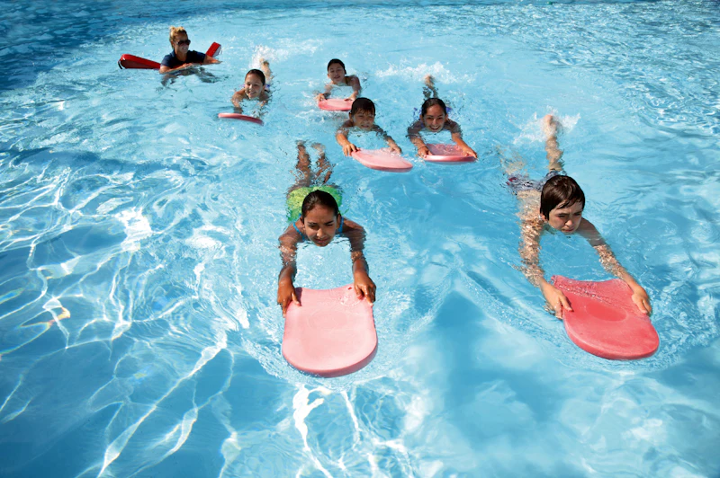 An instructor supporting a young swimmer