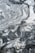 A close-up view of a marble surface showcasing intricate patterns and veins in shades of gray and white. The natural swirls and textures create a dramatic and elegant appearance.