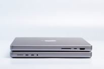 Two sleek, modern laptops are placed on top of each other, highlighting the slim design and metallic finish. Various ports are visible on the side, emphasizing the functionality and technology.