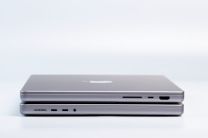 Two sleek, modern laptops are placed on top of each other, highlighting the slim design and metallic finish. Various ports are visible on the side, emphasizing the functionality and technology.