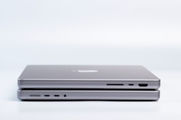 Two sleek, modern laptops are placed on top of each other, highlighting the slim design and metallic finish. Various ports are visible on the side, emphasizing the functionality and technology.