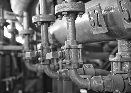 Close-up of interconnected industrial pipes and control systems with a deep blue and parchment color scheme.