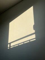 Abstract shadows cast by geometric window frames onto a deep charcoal wall.