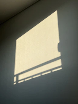 Abstract shadows cast by geometric window frames onto a deep charcoal wall.