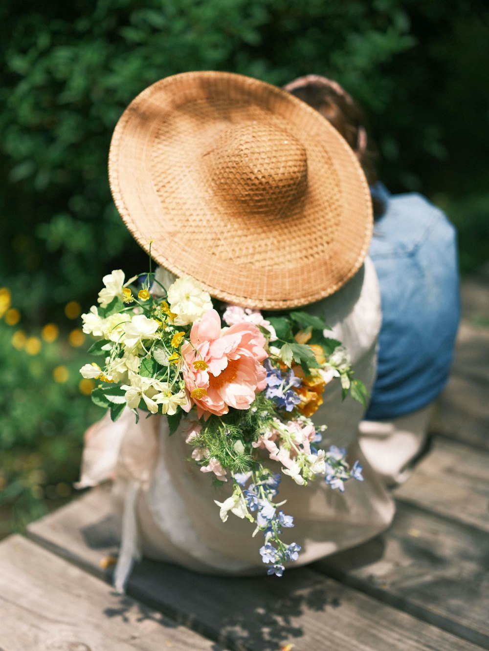 a person wearing a straw hat and holding flowers