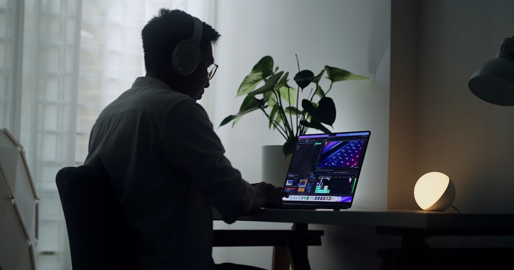 a man wearing a mask and sitting at a desk with a laptop