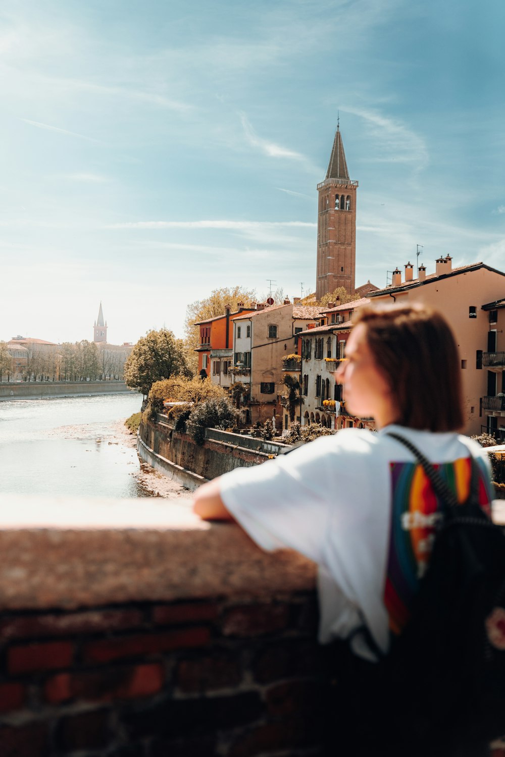 a person sitting on a ledge looking at a clock tower