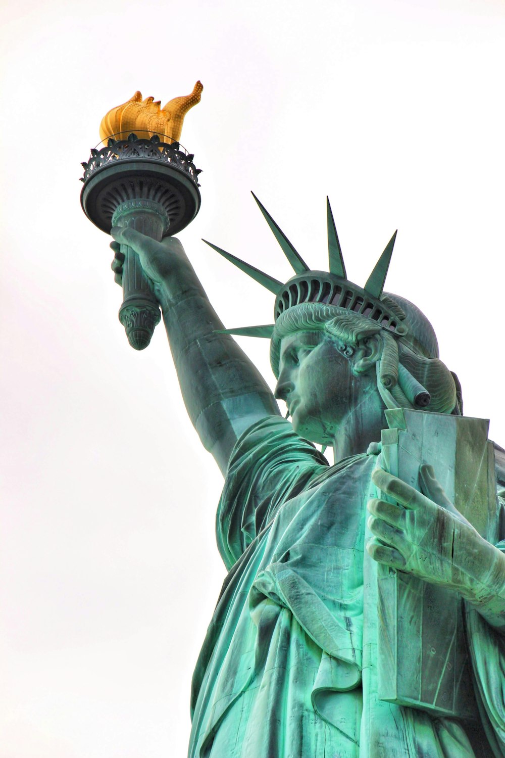 a statue of a person holding a torch with Statue of Liberty in the background