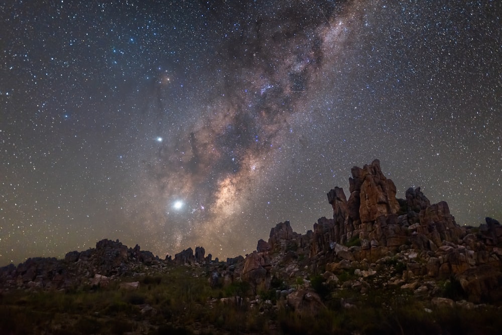 Un paisaje rocoso con estrellas en el cielo