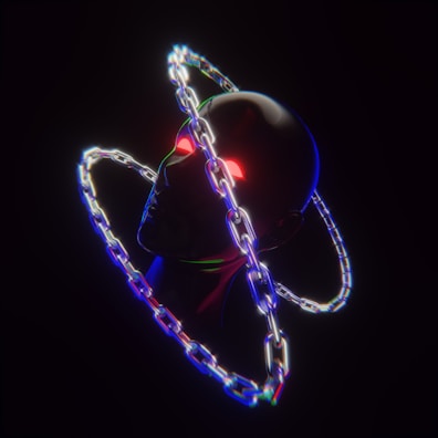 A dark, surreal image featuring a metallic humanoid head with glowing red eyes. It is encircled by two overlapping, luminous chains creating a halo effect. The chains emit multicolored light, casting a reflection on the head, and the overall scene is set against a black background.