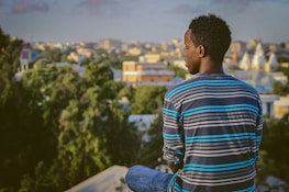 a man sitting on a ledge overlooking a city