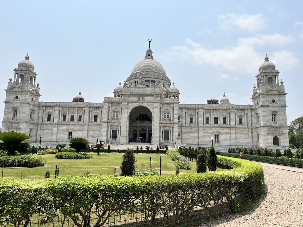 a large white building with a dome and a garden in front of it with Victoria Memorial Hall in the background