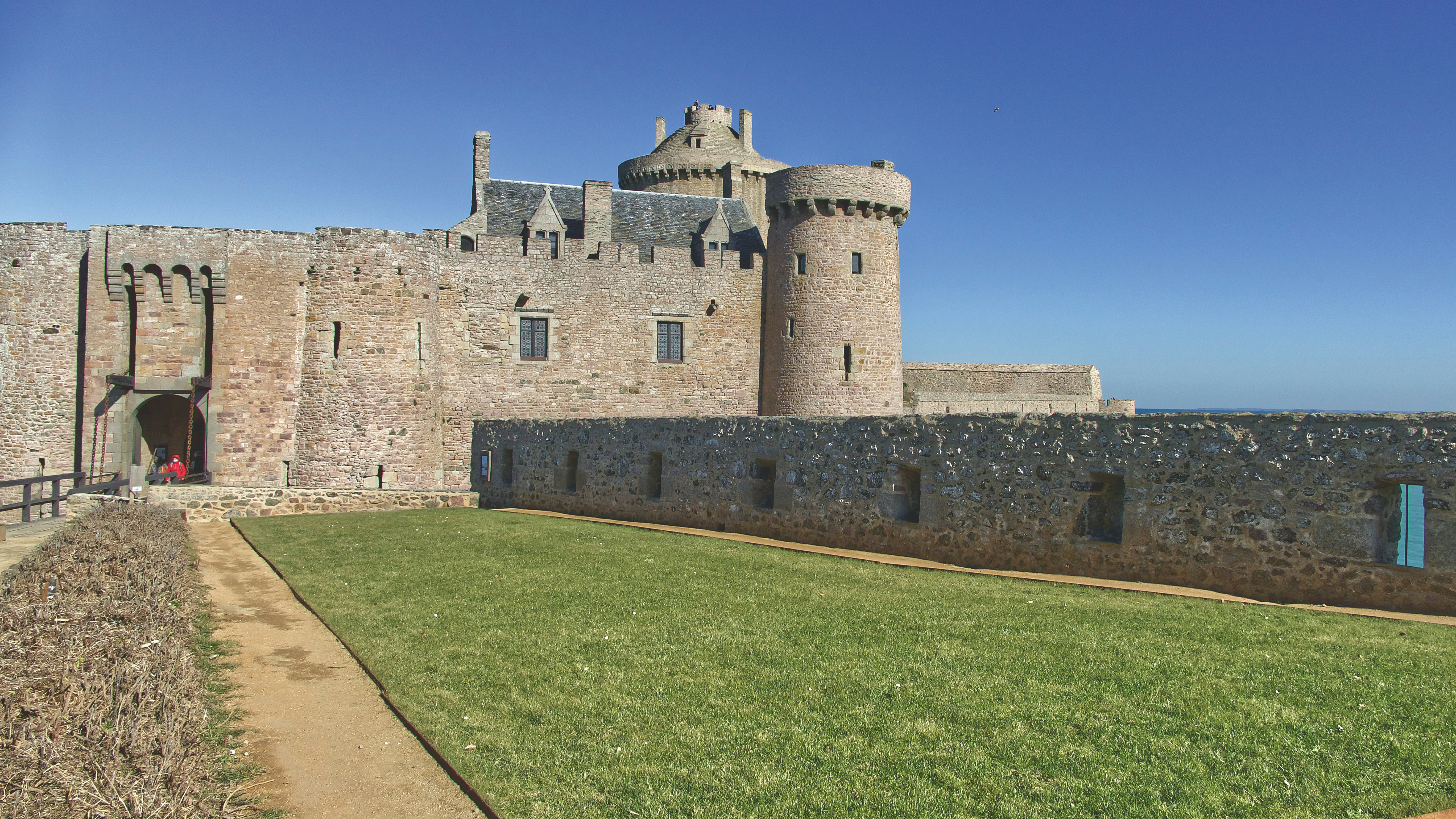 a stone castle with a grass lawn