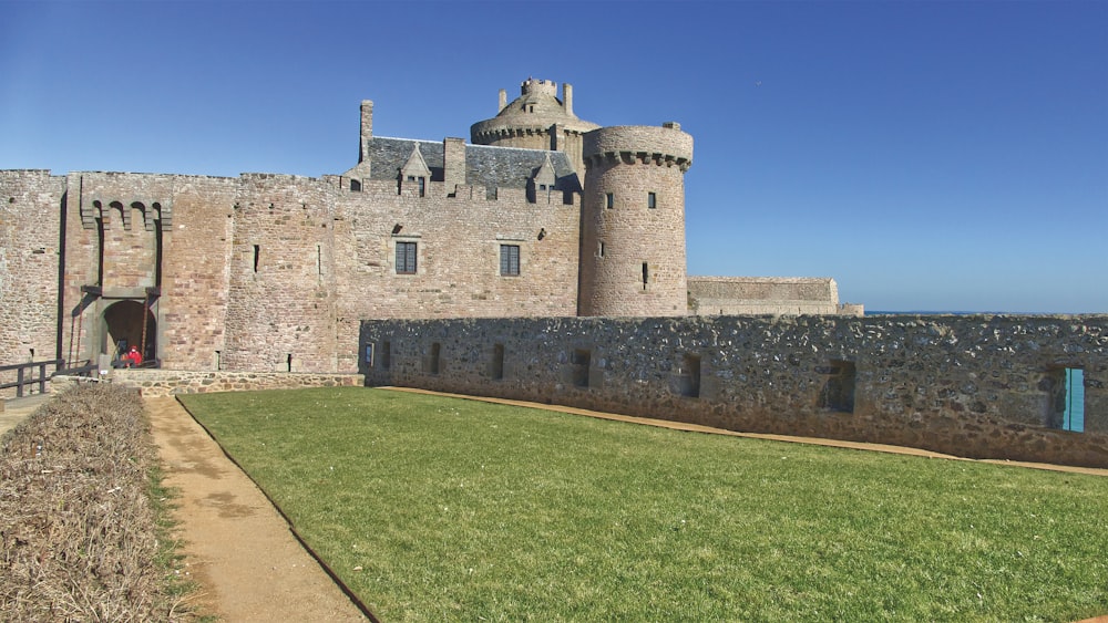 a stone castle with a grass lawn